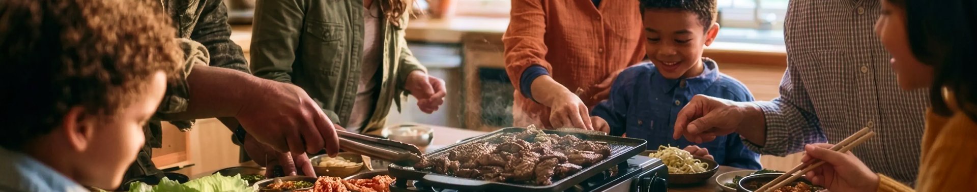 Family sharing Korean BBQ around a tabletop grill